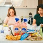 Dwie kobiety rozpakowują zakupy spożywcze w nowoczesnej kuchni