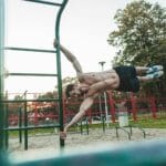 Mężczyzna trenujący kalistenikę na drążkach w miejskim parku