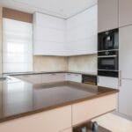 Nowoczesna kuchnia z białymi szafkami, zabudową AGD i kamiennym blatem