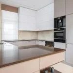 Nowoczesna kuchnia z białymi szafkami, zabudową AGD i kamiennym blatem