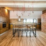 Przestronna loftowa kuchnia z ceglanymi ścianami i drewnianymi akcentami