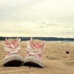 Różowe tenisówki na piaszczystej plaży w Gdańsku o zachodzie słońca