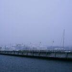 Zamglony zimowy widok na sopocki port z pomostem i zacumowanymi żaglówkami