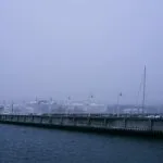 Zamglony zimowy widok na sopocki port z pomostem i zacumowanymi żaglówkami