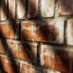 Zbliżenie słonecznej ściany z cegiełek z wyraźną fakturą i cieniami