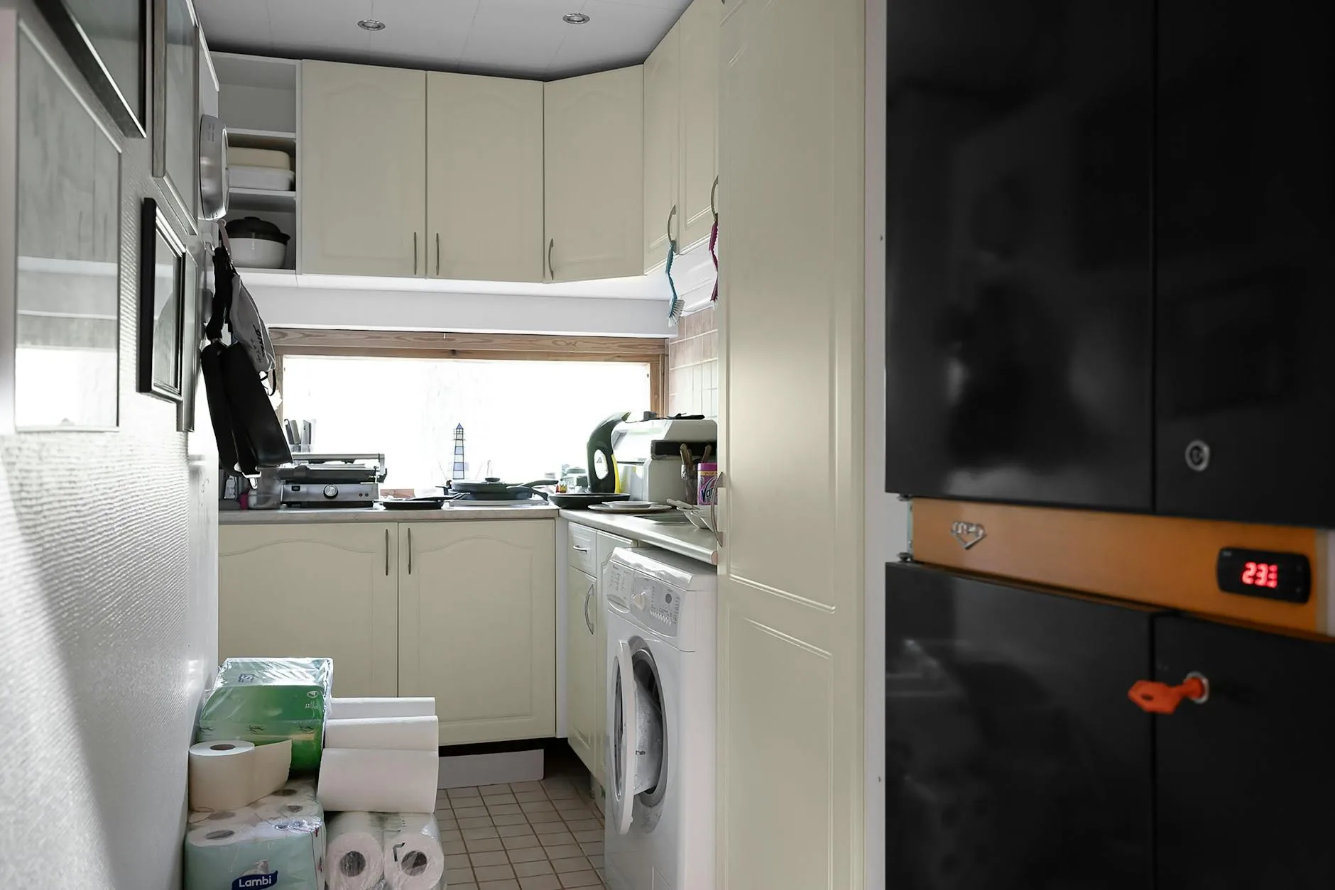 Mała nowoczesna kuchnia z białymi szafkami i pralką pod blatem