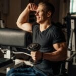 Mężczyzna na wózku inwalidzkim ćwiczy z hantlą na siłowni