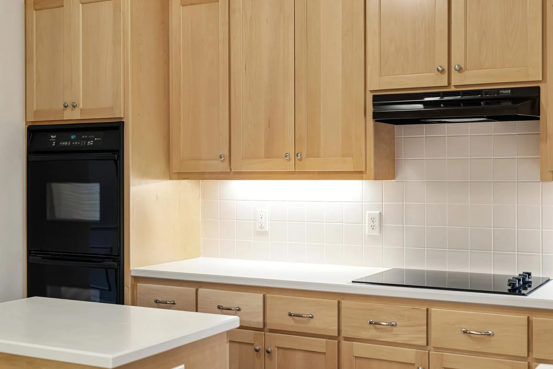 Nowoczesna kuchnia z drewnianymi szafkami, czarnym piekarnikiem i płytą indukcyj