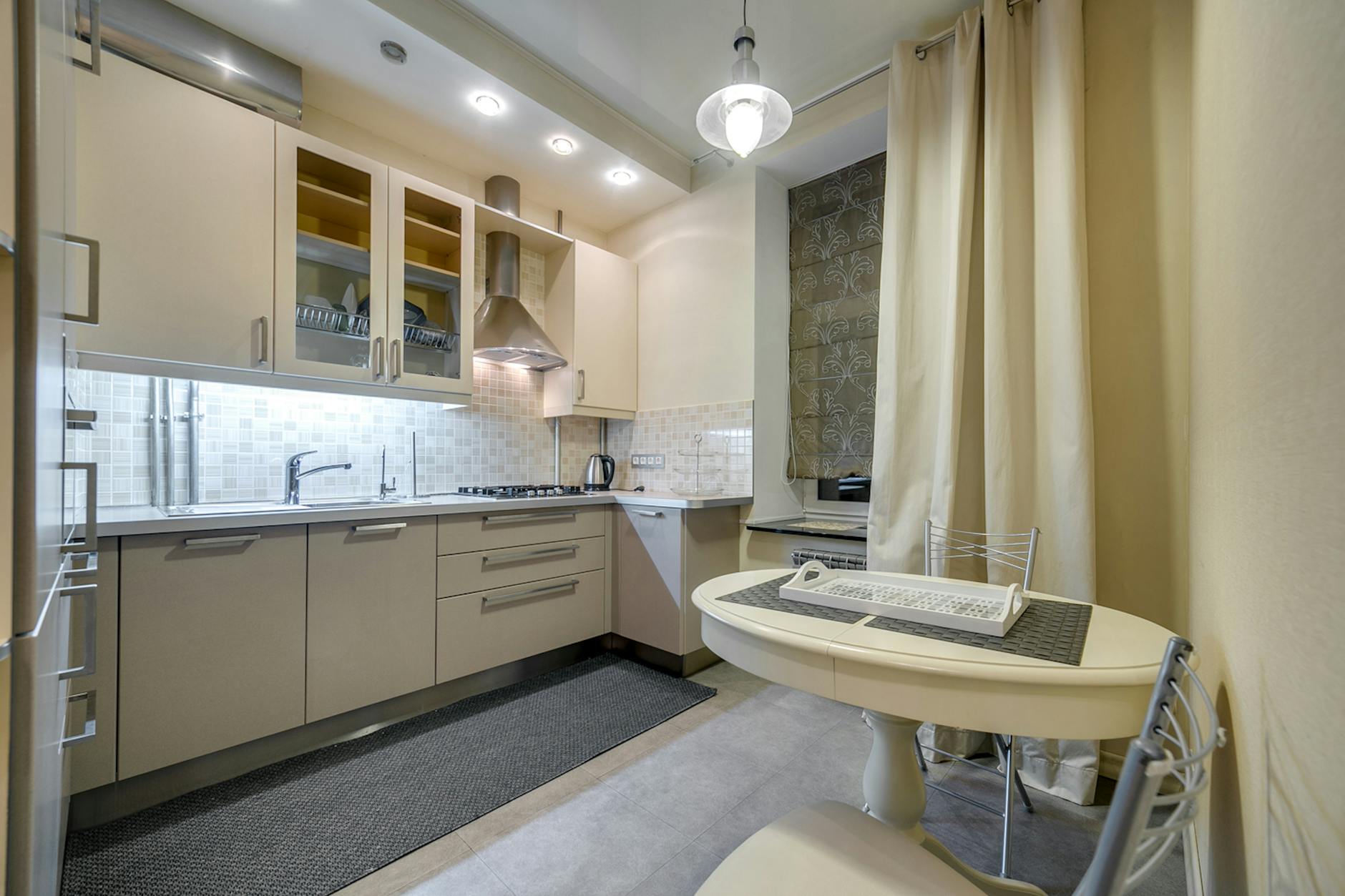 Elegancka beżowa kuchnia z nowoczesnymi szafkami i stołem jadalnym