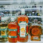 Butelki kolorowych alkoholi ustawione na półkach w sklepowej gablocie
