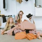 Mama i córka z uśmiechem przeglądają dziecięce ubrania w jasnym pokoju