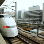 Pociąg Shinkansen wjeżdża na peron zatłoczonej stacji w Japonii