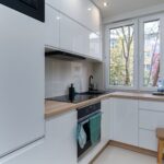 Jasna minimalistyczna kuchnia z białą zabudową i naturalnym światłem