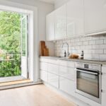Nowoczesna biała kuchnia z widokiem na balkon i jasnym wnętrzem